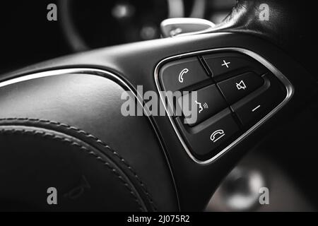 Lenkradbedienungstaste im Luxuswagen mit Lederausstattung. Moderner Fahrzeughintergrund Stockfoto