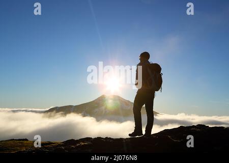 Bergwanderer an den Hängen des Beinn Chuim und Blick auf den sonnenbeschwobenen Gipfel von Ben Lui, der durch die Wolkeninversion in Schottland bricht Stockfoto