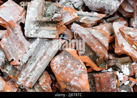 Nahaufnahme eines Haufens alter, schmutziger kaputter Dachziegel. Bau Dachindustrie Hintergrund. Konzept der Renovierung, Abriss, Erdbeben oder Ökologie Stockfoto