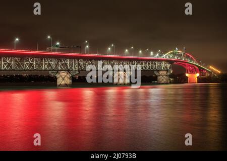 Die Auckland Harbour Bridge in Auckland, Neuseeland, leuchtete am Auckland Anniversary Day rot auf Stockfoto