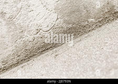 Nahaufnahme der inneren Ecke mit Kalk-Zement-Gipsmischung. Monochromatisches Bild mit selektivem Fokus. Hintergrundtextur der Bauindustrie. Stockfoto