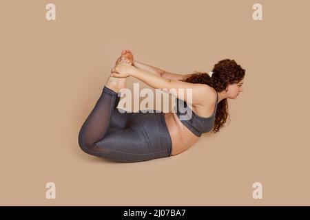 Plump positive Fett barfuß übergewichtige Frau tut Yoga Stretching Position Boot, Bogen Dhanurasana. Pilates-Übung. Stockfoto