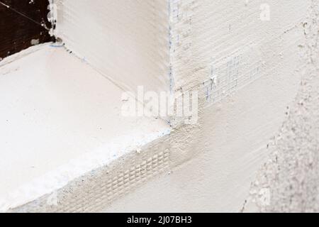 Neu installierte Verputzwinkelperlen mit Kunststoffgewebe an der äußeren Ecke eines Fensters. Selektiver Fokus Stockfoto