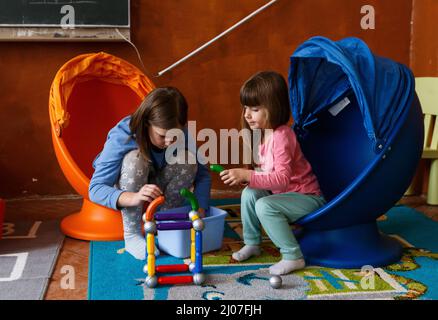 BEREHOVE, UKRAINE - 16. MÄRZ 2022 - Mädchen spielen in einem der Klassenräume des Gabriel Bethlen Berehove Lyzeums, in dem intern Vertriebene untergebracht sind, Stockfoto