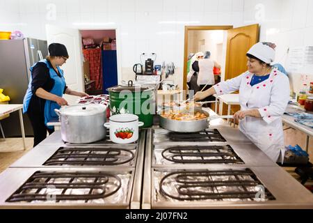 BEREHOVE, UKRAINE - 16. MÄRZ 2022 - Frauen kochen in der Küche des Gabriel Bethlen Berehove Lyzeums, das intern Vertriebene beherbergt, Bereh Stockfoto