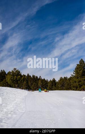 Junge Paar Skifahrer Mann und Frau, die in Snowboardausrüstung nicht erkennbar sind, maskiert weit weg auf dem Hintergrund schneebedeckter Berge hoch bei einem Ski Stockfoto