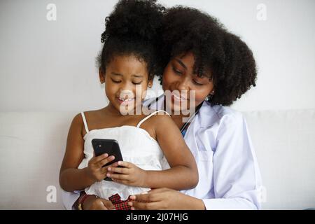 Portrait of a Brilliant Black Girl with Braces schreibt in Exercise Notebook, Smiles. Junior Classroom mit verschiedenen Gruppen von Kindern, die Neues lernen Stockfoto