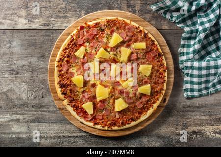 Hawaiianische Pizza mit Ananas, Schinken und Käse auf einem Holztisch Stockfoto