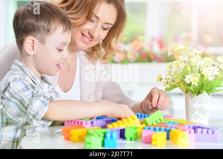 Frau und kleinen Jungen spielen mit bunten Kunststoff Blöcke zusammen Stockfoto