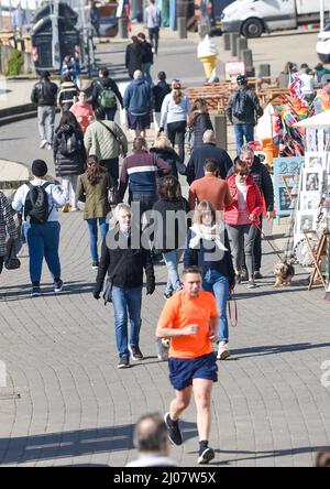 Brighton UK 17. March 2022 - Besucher genießen die Frühlingssonne an der Strandpromenade und am Strand von Brighton, da für Großbritannien in den nächsten Tagen warmes Wetter prognostiziert wird : Credit Simon Dack / Alamy Live News Stockfoto