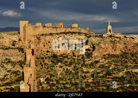 Muralla de Jairán - Verteidigungsmauer, die von König Jairan im 11.. Jahrhundert erbaut wurde, dunkle Regenwolken über der karden Landschaft von Almeria in Südspanien. Stockfoto