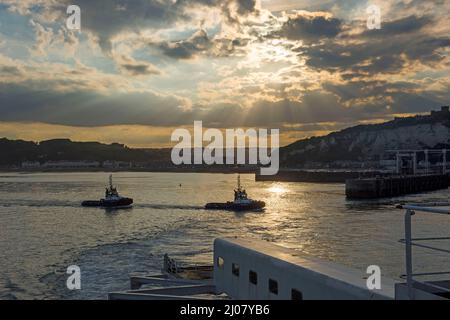 Ein Paar Schlepper im Hafen von Dover in England, Großbritannien, gesehen vom Deck einer P&O Fähre bei Sonnenuntergang. Stockfoto