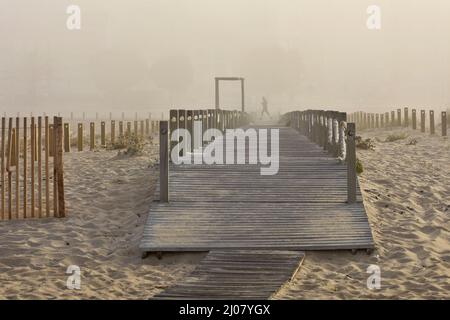 Holzsteg, Mann, der im Morgennebel am Strand läuft, Figueira da Foz Portugal. Stockfoto