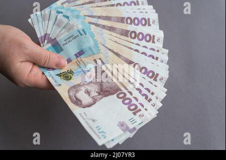 Eine Nahaufnahme der Hand einer Frau, die Geld hält. Eine Erwachsene Frau, die ukrainische Banknoten hält. Bargeld im Wert von 1.000 Griwna. Selektiver Fokus. Stockfoto