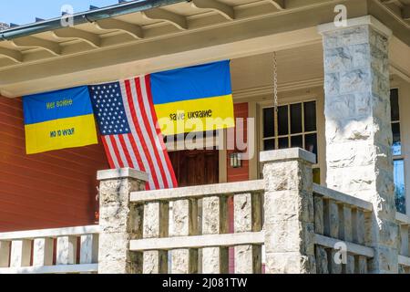 NEW ORLEANS, LA, USA - 15. MÄRZ 2022: US-Flagge und ukrainische Flaggen hängen von der Veranda des Hauses in Uptown New Orleans Stockfoto