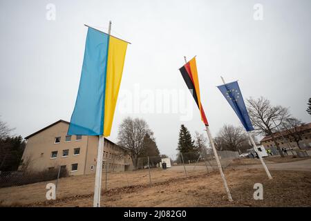 17. März 2022, Baden-Württemberg, Meßstetten: Flaggen der Ukraine, Deutschlands und der Europäischen Union fliegen vor den Gebäuden der ehemaligen Zollernalb-Kaserne. In den letzten Tagen wurde in der ehemaligen staatlichen Erstaufnahmeeinrichtung im Bezirk Zollernalb ein Ankunftszentrum für Flüchtlinge aus der Ukraine eingerichtet., Foto: Marijan Murat/dpa Stockfoto