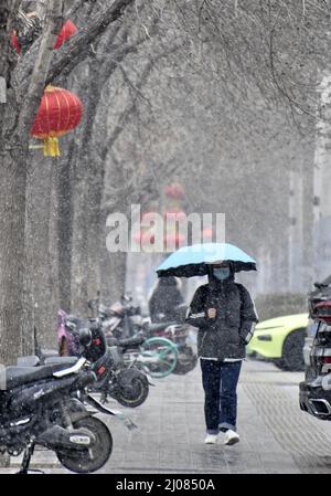 (220317) -- PEKING, 17. März 2022 (Xinhua) -- Menschen laufen im Schnee in Peking, der Hauptstadt Chinas, 17. März 2022. Chinas meteorologische Behörden gaben am Donnerstag eine blaue Warnung für schweren Schnee im nördlichen Teil des Landes aus. (Xinhua/Li Xin) Stockfoto