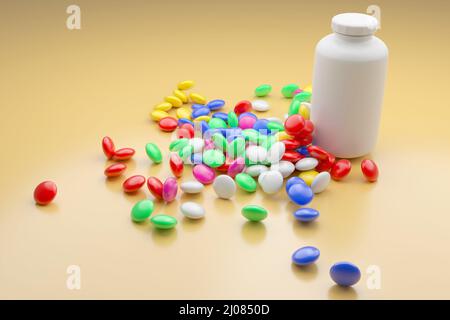 Rote, blaue, weiße, gelbe, grüne Dragees auf der gelben Oberfläche. Stockfoto