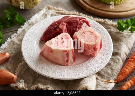 Knochenmark und Fleisch mit frischem Gemüse, bereit für die Zubereitung einer hausgemachten Brühe oder Suppe Stockfoto