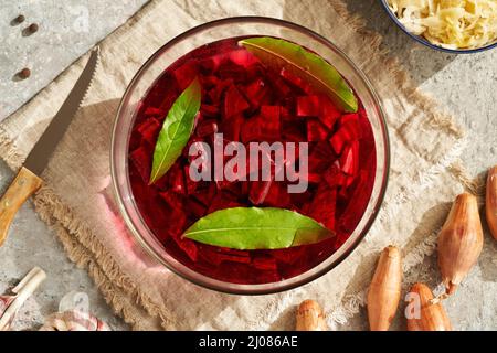 Zubereitung von fermentierten roten Rüben-Kvass mit Zwiebeln, Knoblauch und Lorbeerblatt Stockfoto
