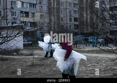 Kunststofffolien werden an die Bewohner verteilt, um defekte Fenster zu reparieren. Nachbarn und Freiwillige helfen bei der Reinigung von Trümmern und Glasscherben, nachdem ein Raketenangriff auf ein Wohngebiet in Kiew am Morgen des 17.. März 2022 Wohngebäude und ein örtliches Gymnasium beschädigt hatte. Kiew, Ukraine. Russische Streitkräfte betraten am 24. Februar 2022 das Territorium der Ukraine. (Foto von Justin Yau/ Sipa USA) Stockfoto