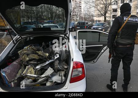 Ein ukrainischer Polizist bewacht Teile einer explodierten russischen Rakete. Nachbarn und Freiwillige helfen bei der Reinigung von Trümmern und Glasscherben, nachdem ein Raketenangriff auf ein Wohngebiet in Kiew am Morgen des 17.. März 2022 Wohngebäude und ein örtliches Gymnasium beschädigt hatte. Kiew, Ukraine. Russische Streitkräfte betraten am 24. Februar 2022 das Territorium der Ukraine. (Foto von Justin Yau/ Sipa USA) Stockfoto