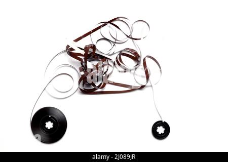 Alte Kassette mit aufgewickeltes Klebeband. Beschädigtes Datenträger für alte Tonaufnahmegeräte. Weißer Hintergrund. Stücke von einem alten Vintage-Kassettenband Stockfoto