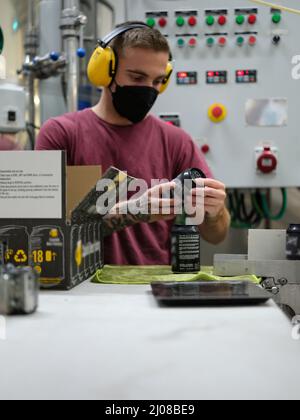Arbeiter, die das Etikett auf einer Bierkisten lesen, bevor sie es für den Versand verpacken Stockfoto