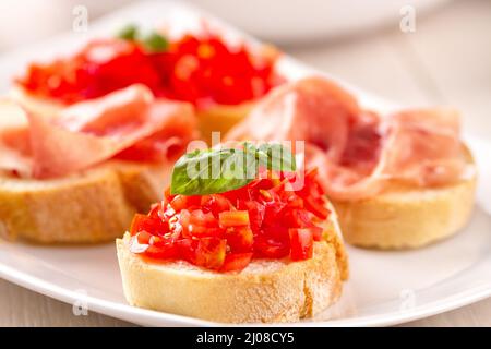 Italienische Vorspeise-Bruschetta mit Parmaschinken und frischen Tomaten auf einem Teller Stockfoto