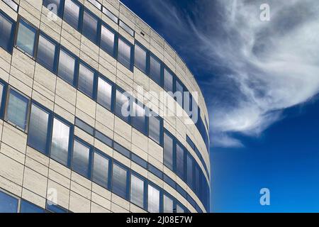 Düsseldorf, Deutschland - März 9. 2022: Blick auf den Rand der gewölbten Gebäudefassade mit weißer Natursteinfassade, blauen Fenstern gegen klaren Himmel mit Stockfoto