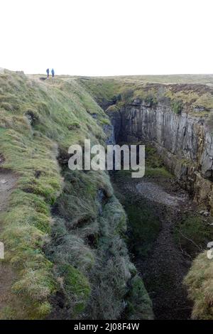 Zwei Männer, die am Rande des Hull Pot in der Nähe von Pen-y-ghent (einem der Yorkshire 3 Peaks) Horton in Ribblesdale, Yorkshire Dales National Park, England, spazieren gehen. Stockfoto