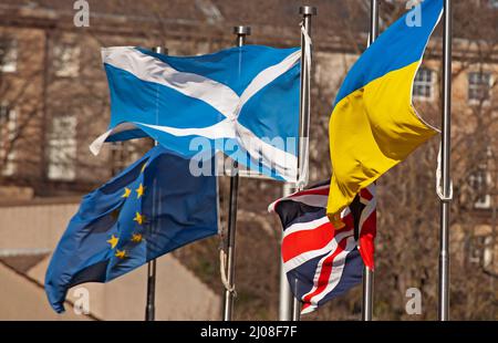 Holyrood, schottisches Parlament, Edinburgh, Schottland, Großbritannien. 17.. März 2022. Vor dem Gebäude des schottischen Parlaments wehten verwickelte Flaggen im regen Wind. Im Bild: Flaggen, die vor dem schottischen Parlament fliegen, scheinen die Turbulenzen zu illustrieren, die mit der Europäischen Union, der Ukraine, dem Vereinigten Königreich und Schottland vor sich gehen. Protest der Ukraine: „Wir verurteilen die rechtswidrige russische Invasion in dieses demokratische Land“ Kredit: Archwhite/Alamy Live News Stockfoto