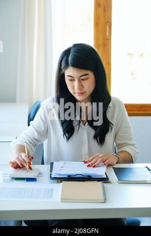 Konzeptionsprüfer, Finanziers, weibliche Mitarbeiter, die Rechenmaschinen vorbringen und Abschlüsse dokumentieren, Risiken bewerten und Investitionen planen Stockfoto