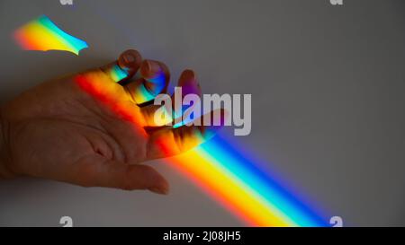 Regenbogenstrahl auf der Hand einer Frau. Stockfoto