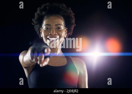 Du bist der nächste auf meiner Liste. Studioaufnahme einer jungen Sportlerin, die vor dunklem Hintergrund mit dem Finger auf die Kamera zeigt. Stockfoto