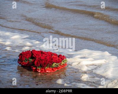 Die Liebe hat vielleicht verloren, roter Rosenkranz, von der Flut hochgespült. Stockfoto