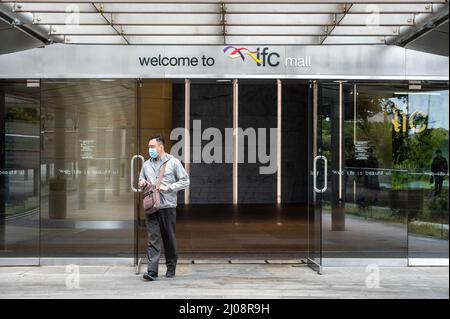 Ein Mann mit einer OP-Maske verlässt die IFC Mall im Central Business District von Hongkong. Nach der wirtschaftlichen Analyse der Regierung von Hongkong steht der Einzelhandel kurzfristig unter immensem Druck, da die Pandemie und die damit verbundenen sozialen Distanzierungsmaßnahmen eine Herausforderung für eine Wiederbelebung darstellen. Stockfoto