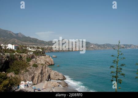 Kleine Bucht im Mittelmeer, Nerja, Costa del Sol, Provinz Malaga, Andalusien, Spanien. Blick auf die Berge, Badegäste, Sonnenschirme, Liegen Stockfoto