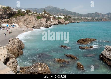 Kleine Bucht im Mittelmeer, Nerja, Costa del Sol, Provinz Malaga, Andalusien, Spanien. Blick auf die Berge, Badegäste, Sonnenschirme, Liegen Stockfoto