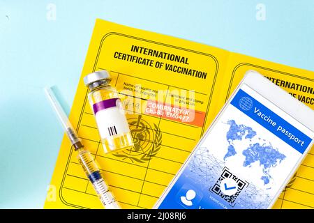 Gelber Impfpass, Impfflasche, Spritze und Smartphone mit gültigem digitalen Impfzertifikat QR-Code für COVID-19. Impfung Stockfoto