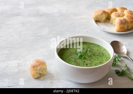 Gesunde Grünkohl-Cremesuppe mit Kartoffeln und Brot auf grauem Hintergrund mit freiem Platz. Einfache hausgemachte Speisen Stockfoto