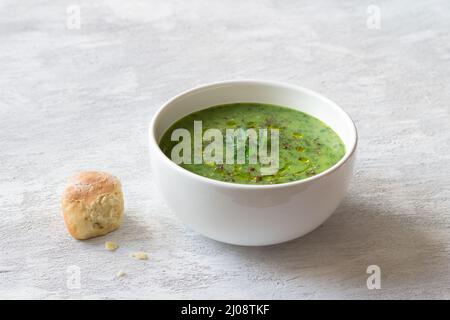 Gesunde Grünkohl-Sahnesuppe mit Kartoffeln und Brot auf grauem Hintergrund. Einfache hausgemachte Speisen Stockfoto