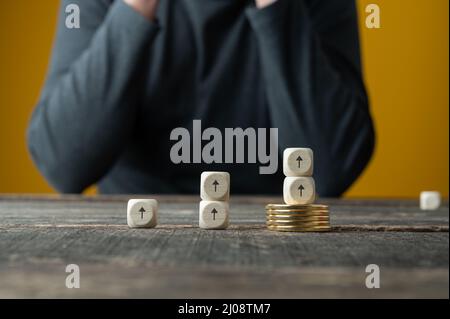 Konzeptuelles Bild des Goldmarktes – Stapel goldener Münzen und Pfeile, die nach oben zeigen und das Wachstum des Goldpreises anzeigen. Stockfoto