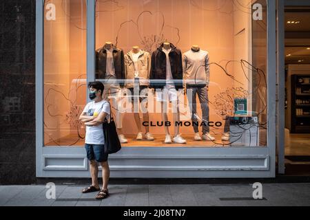 Hongkong, China. 16. März 2022. Eine Person, die eine OP-Maske trägt, steht vor einem Club Monaco-Geschäft im zentralen Geschäftsviertel von Hongkong. Nach der wirtschaftlichen Analyse der Regierung von Hongkong steht der Einzelhandel kurzfristig unter immensem Druck, da die Pandemie und die damit verbundenen sozialen Distanzierungsmaßnahmen eine Herausforderung für eine Wiederbelebung darstellen. (Bild: © Ben Marans/SOPA Images via ZUMA Press Wire) Stockfoto