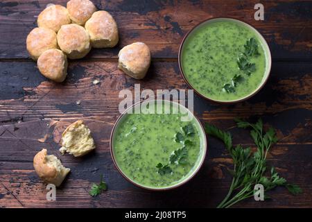 Gesunde Grünkohl-Kartoffeln Sahnesuppe und Brot auf Holzgrund. Einfache hausgemachte Speisen Stockfoto