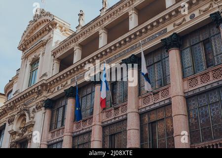 Nizza, Frankreich - 10. März 2022: Flaggen an der Vorderseite der Opera de Nice, dem wichtigsten Opernhaus in Nizza, in dem das Ballett Mediterrannee und das Th untergebracht sind Stockfoto