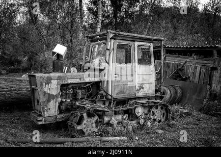 Alter rostiger Traktor, der im Hinterhof geparkt hat Stockfoto