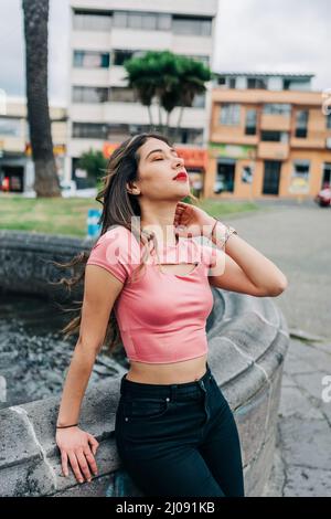 Attraktive junge lateinische Frau, die tagsüber die Sonne genießt, Make-up, Freizeitkleidung, lange blonde Haare, Lifestyle in der Stadt, Mode und Schönheit Stockfoto