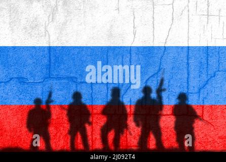 Russische Flagge auf einer Betonwand mit Soldaten Schatten gemalt. Krise in den internationalen Beziehungen, russische militärische Invasion der Ukraine Stockfoto