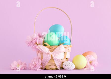Pastell ostereier in einem Korb mit rosa Hintergrund Stockfoto